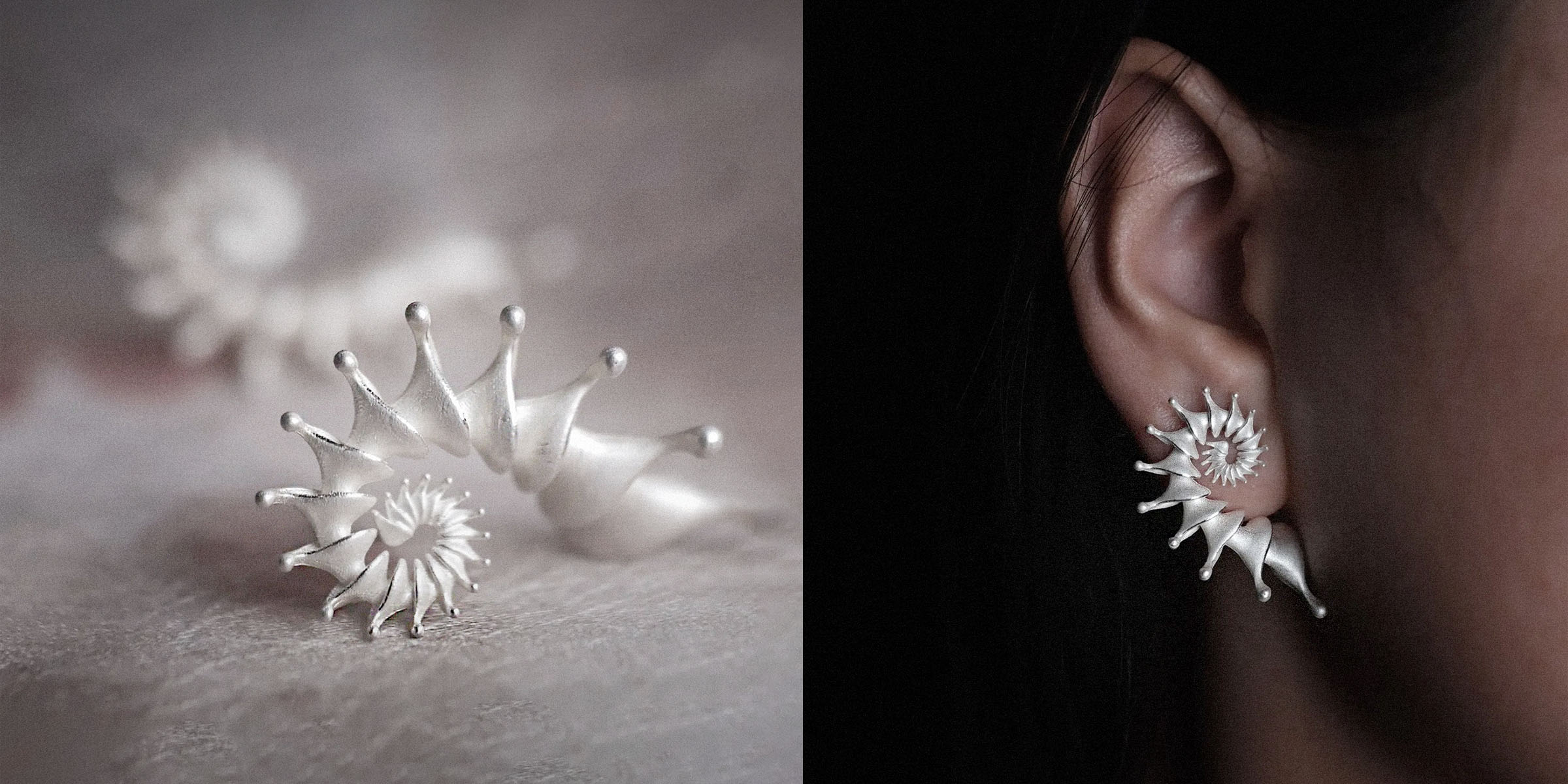 A pair of Spira Earrings resting on textured fabric, highlighting their spiral form and shine.